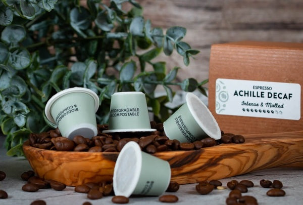 The Achille Decaf nespresso pods on a stack of coffee beans.