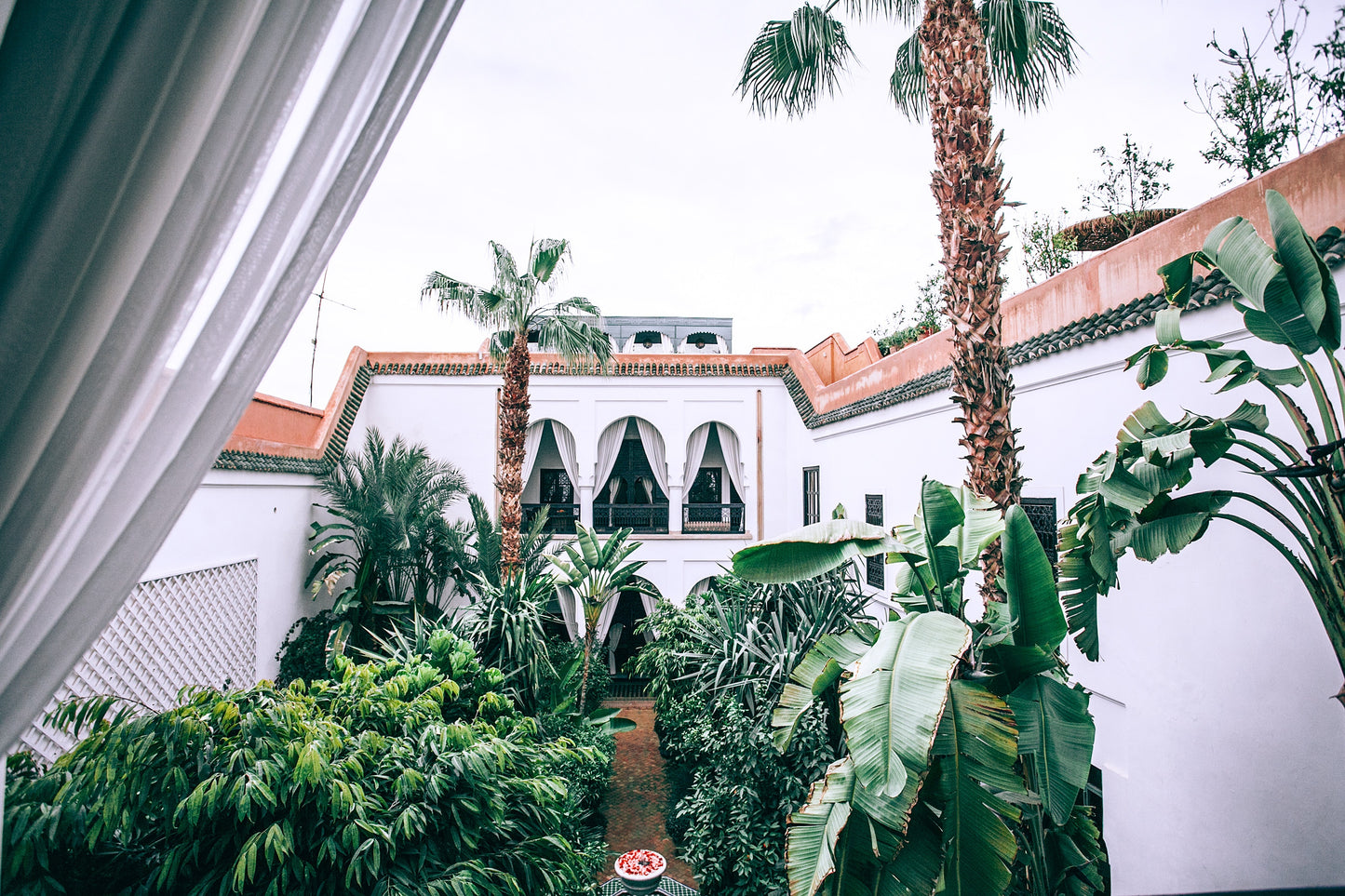 White mansion patio with lush tropical trees. 