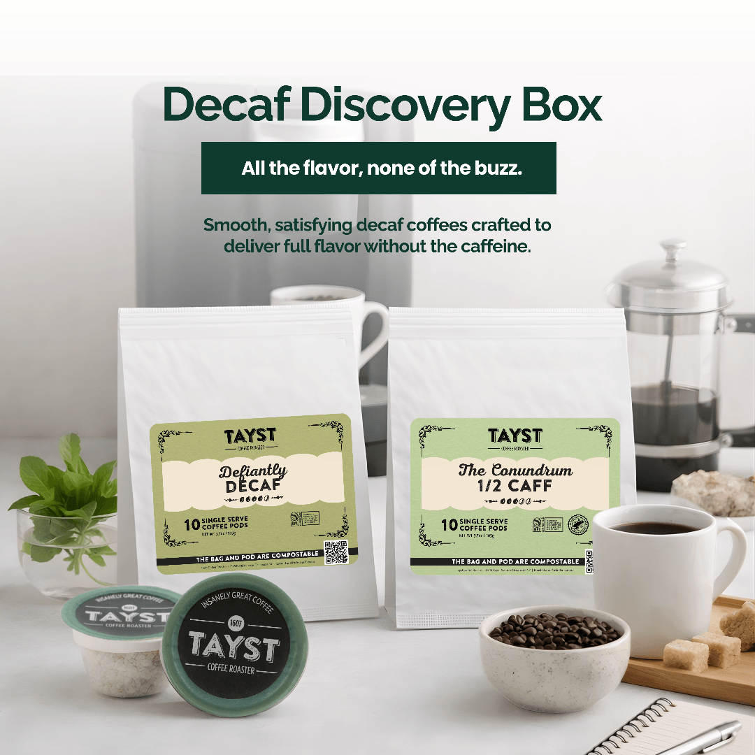 Decaf Discovery Box with coffee packaging and brewing equipment on a white surface.