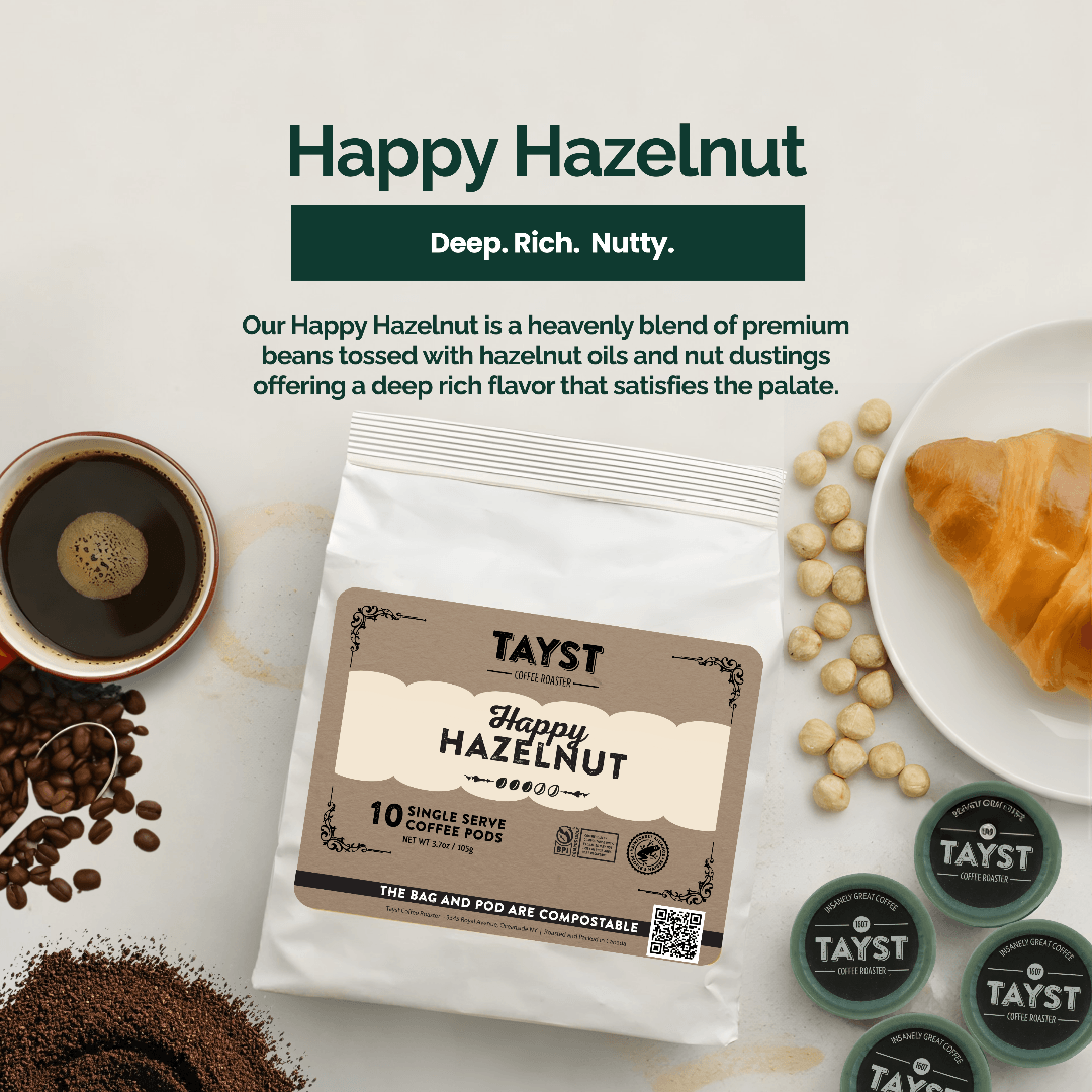 TAYST Happy Hazelnut coffee package with coffee beans, a cup of coffee, and a croissant on a white background.