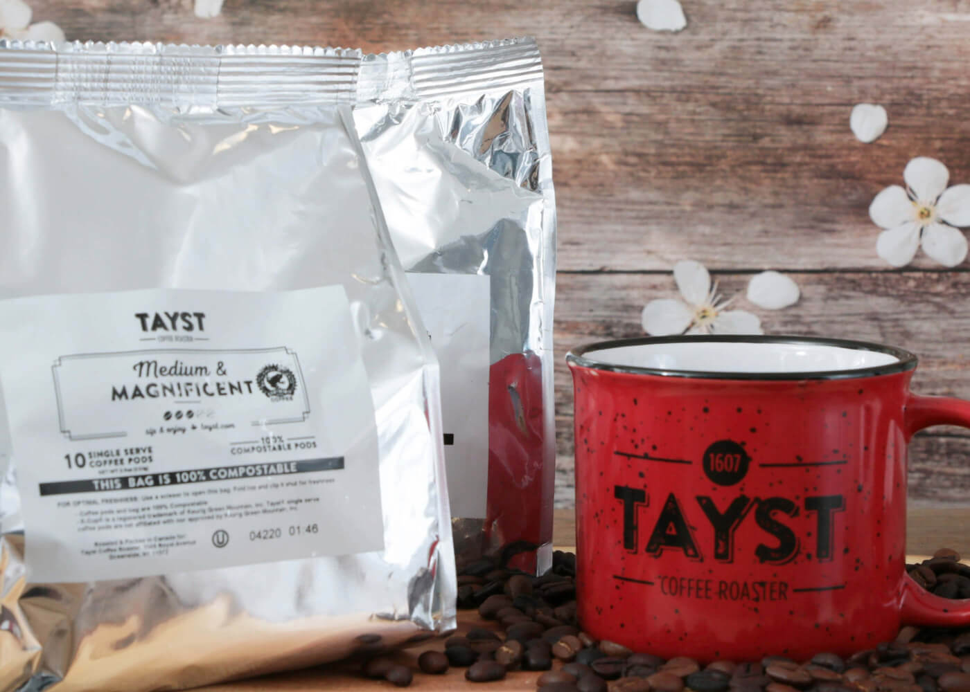 Red mug and coffee packages with 'TAYST' branding on a wooden surface.