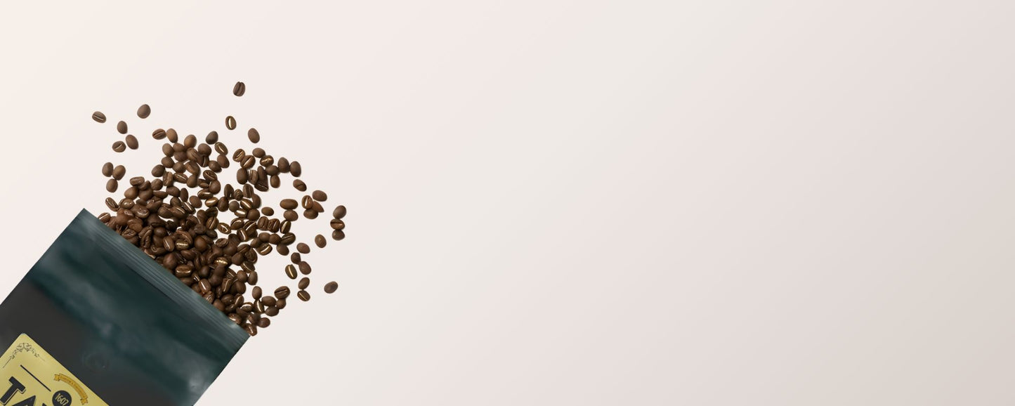 Open bag of coffee beans spilling out onto a light background