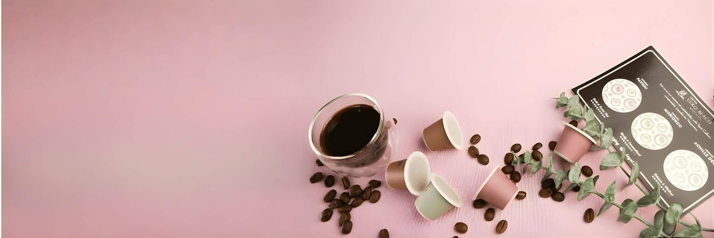 Coffee cup, tayst nespresso capsules, and coffee beans on a pink surface
