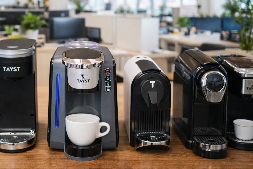 Row of coffee machines on a wooden table with a blurred office background