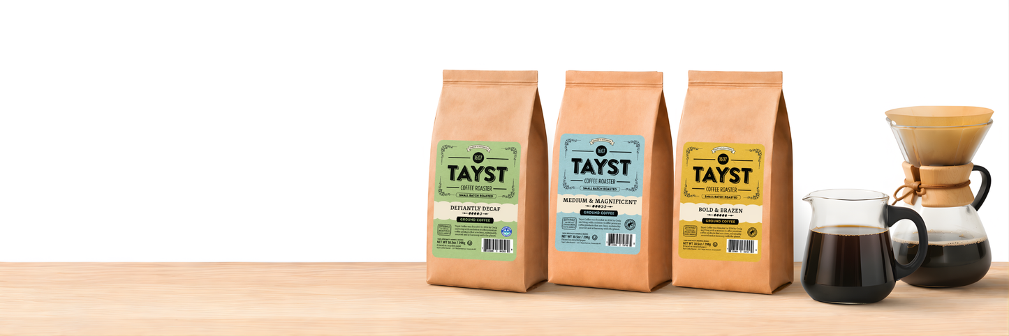 Tayst coffee bags including decaf, medium roast, and bold roast next to a pour-over coffee brewer and glass carafe