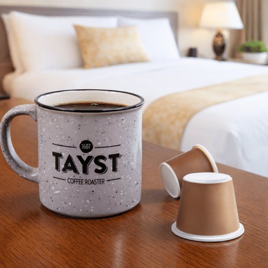 Tayst mug with coffee and nespresso capsules on a table in a hotel bedroom setting