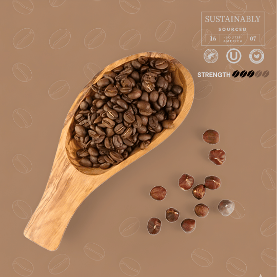 Wooden scoop filled with tayst hazelnut beans on a brown background with coffee bean patterns.