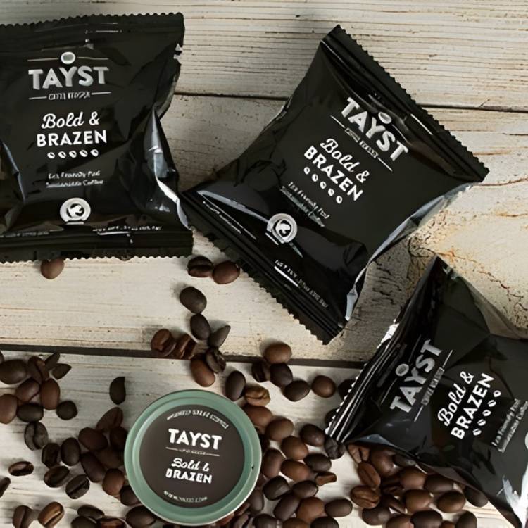 Tayst coffee singles and coffee beans on a wooden surface